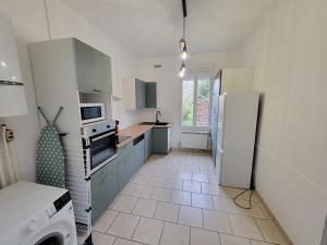 a kitchen with white cabinets and a refrigerator at Maison proche gare in Margny-lès-Compiègne