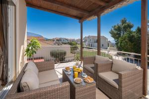 a patio with wicker chairs and a table on a balcony at Gerasimos Dream House - 7 Minutes from the Airport in Lakíthra