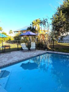 a swimming pool with two chairs and an umbrella at Driftwood Getaway Vacation home in Fort Myers Beach