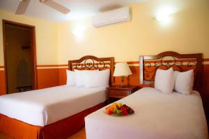 Zwei Betten in einem Hotelzimmer mit einer Obstschale in der Unterkunft Maya Campeche Hotel in Campeche