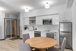 a kitchen with a wooden table and chairs in it at Lux Suites Extended Stay in Thunder Bay