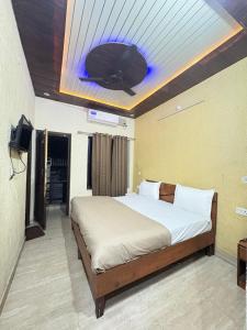 a bedroom with a bed and a tv on the ceiling at HOTEL O DEV RAJ Homestay in Rishīkesh +8 photos