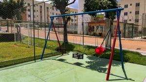 a swing set in a park with a fence at Aconchego e praticidade ao lado da BR-040 in Luziânia