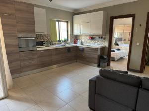 a kitchen with wooden cabinets and a couch in a room at Tommy's Retreat Xewkija in Xewkija +9 photos