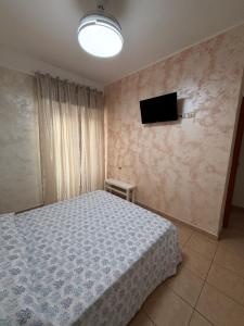 a bedroom with a bed and a tv on the wall at Ludovica's house 2 in Giardini Naxos