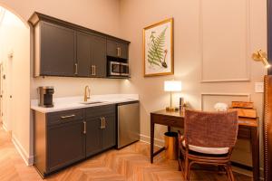 a kitchen with black cabinets and a desk with a chair at Sinclair Suites - Boutique Hotel West Dundee in West Dundee
