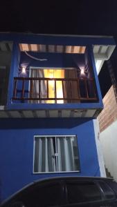 a blue building with a balcony with a car parked in front at Onda's suíte in Paraty