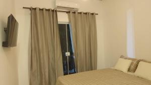 a bedroom with a bed and a window with curtains at Onda's suíte in Paraty