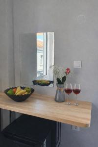 a table with a bowl of fruit and two glasses of wine at Mézzo Lago in Missolonghi