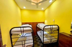 three bunk beds in a room with a yellow wall at Hostal los Cheles in León