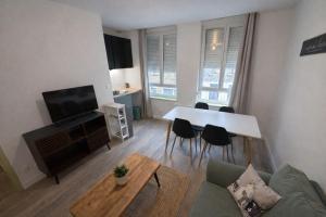 a living room with a couch and a table with chairs at Douce Escale - 1 chambre - literie premium in Calais