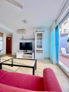 a living room with a red couch and a tv at Alma Marina Alcossebre - WiFi - Pet friendly - Aire Acondicionado in Alcossebre