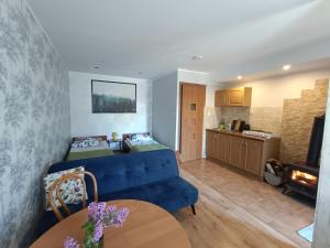 a living room with a blue couch and a kitchen at Agroturystyka Wypoczynek na Wsi in Słowiki Nowe