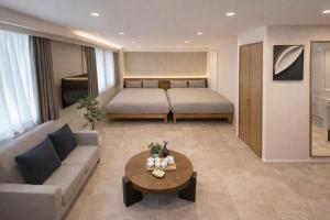 a living room with a couch and a bed at AKATSUKI HOTEL Ueno JR山手線鶯谷駅まで徒歩3分 成田空港直行 新宿渋谷直通 in Tokyo