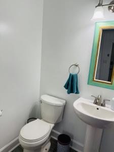 a white bathroom with a toilet and a sink at Retro Retreat in Wilson