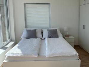 a bed with white sheets and pillows in a room at Duna Panoráma Vendégház in Mohács