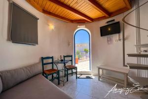 a living room with a table and chairs and a tv at Ξενώνες Ανεμόμυλοι - Windmills Hotel in Panayía