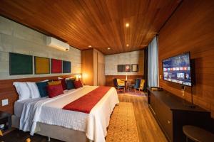 a bedroom with a bed and a flat screen tv at Pousada Recanto do Sambaqui in Balsa Nova