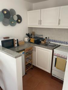 a kitchen with white cabinets and a sink and a microwave at Campos Essencia in Arganil