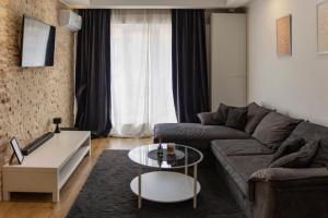 a living room with a couch and a table at Seyra Home Studio - Modern Flat Pool Free Parking Self Check-in in Ştefăneştii de Sus