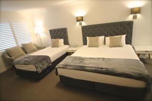 a hotel room with two beds and two nightstands at Quays Hotel in Batemans Bay