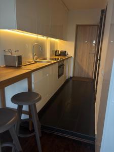 a kitchen with a counter and a sink and two stools at Cosy Newtown apartment in Vilnius