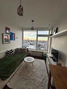 a living room with a bed and a large window at Cosy Newtown apartment in Vilnius
