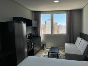a hotel room with a bed and a kitchen with a window at Town Co - Apartment 1004 in Porto Alegre