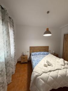 a bedroom with a bed with a white comforter at Alfarnate Antiguo Cuartel in Alfarnate