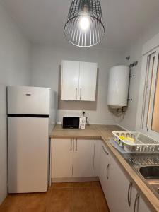 a kitchen with white cabinets and a white refrigerator at Alfarnate Antiguo Cuartel in Alfarnate