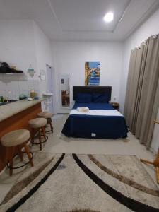 a bedroom with a blue bed and a kitchen at Durmaaquislz in São Luís