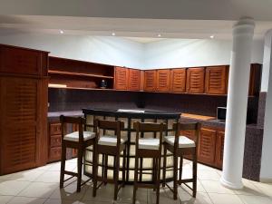 a kitchen with wooden cabinets and a table with stools at Luciana annexe in Mbour
