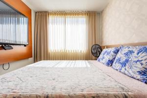 a bedroom with a bed with blue pillows and a window at Apt conforto 2 suítes Dfplaza in Brasília