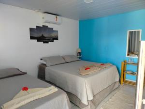 a bedroom with two beds and a blue wall at Casa Noronha tropical 2 in Fernando de Noronha
