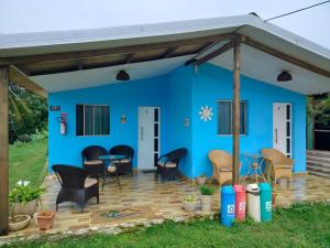 a blue house with chairs and tables on a deck at Casa Noronha tropical 2 in Fernando de Noronha