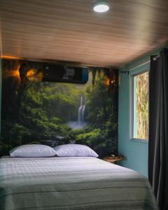 a bedroom with a waterfall mural on the wall at Kibutz Eco Guesthouse in Fortuna