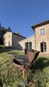 a grill sitting in the grass in front of a house at Antico Casale Mevania in Bevagna
