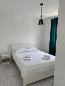 a bedroom with a white bed and a green curtain at Duo Apartments in Bar