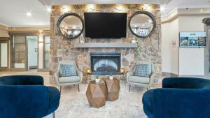 a living room with a stone fireplace with a flat screen tv at Sandman Hotel & Suites Kelowna in Kelowna
