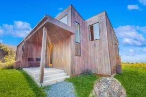 a wooden house in a field with a rock at Wild Meadow in Sea Ranch
