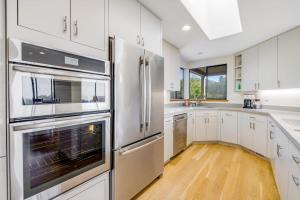 a kitchen with white cabinets and stainless steel appliances at Heron's Nest in Sea Ranch