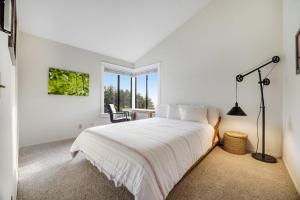 a white bedroom with a bed and a window at Greencroft Meadows in Sea Ranch