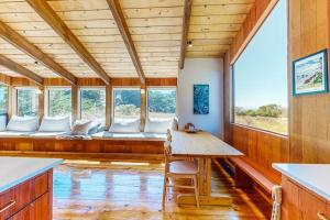 a room with a table and chairs and windows at Dune Drift in Sea Ranch