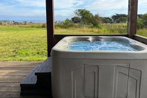 a hot tub on a porch with a view of a field at Coastal Calm at Sea Ranch in Sea Ranch