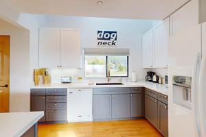 a kitchen with white cabinets and a large window at Blue Mermaid in Sea Ranch