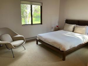 a bedroom with a bed and a chair and a window at Madrone Meadow in Sea Ranch