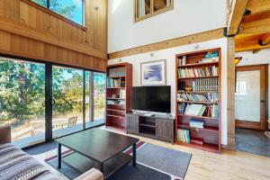 a living room with a tv and bookshelves at Ocean Pines Lodge in Sea Ranch