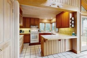 a kitchen with wooden cabinets and white appliances at Cypress Cove in Sea Ranch