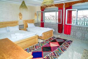 a bedroom with two beds and a rug at Hotel De La Vallée in Aït Baha