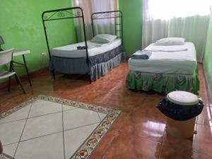 two beds in a room with green walls and a tile floor at Casa MONTOCO 114 in Managua +59 photos